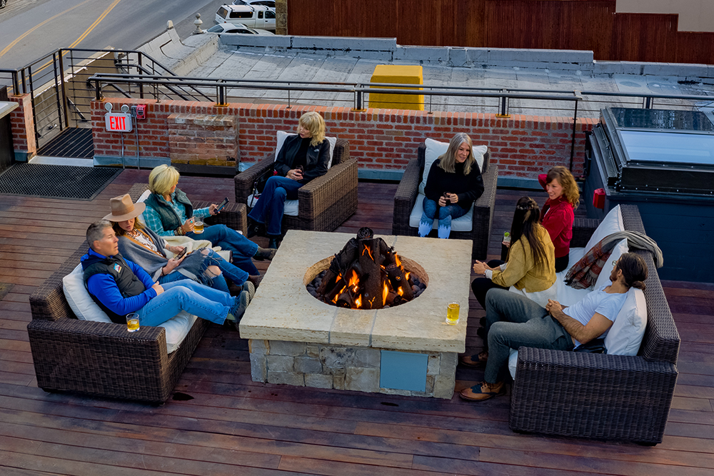 Arial image of people socializing around the fire at the Imogene's rooftop bar.